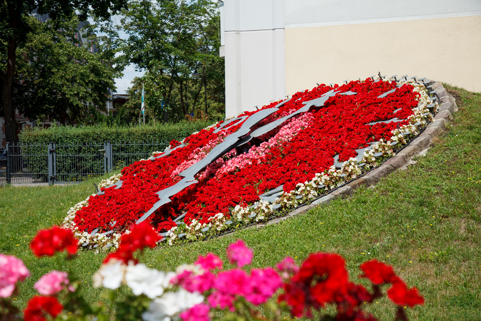Seitlicher Blick auf rot-bepflanzte Blumenuhr
