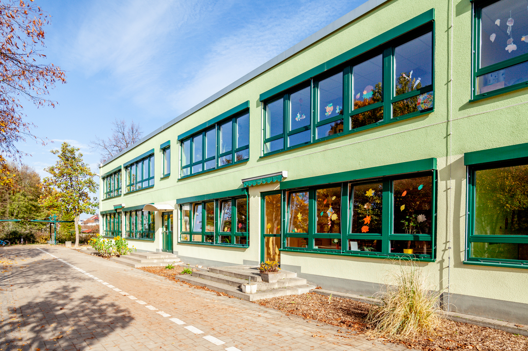 grünes Gebäude mit großen Fensterfronten