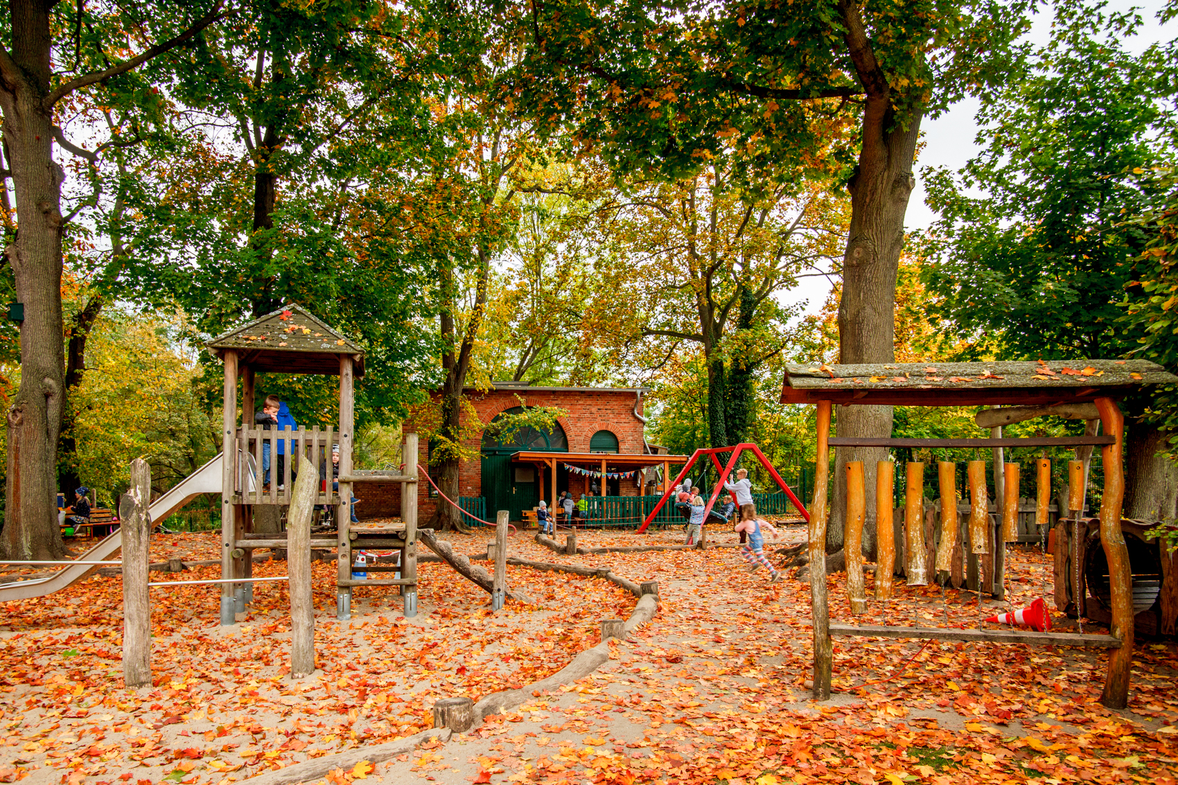 Spielplatz unter Bäumen mit viel Herbstlaub