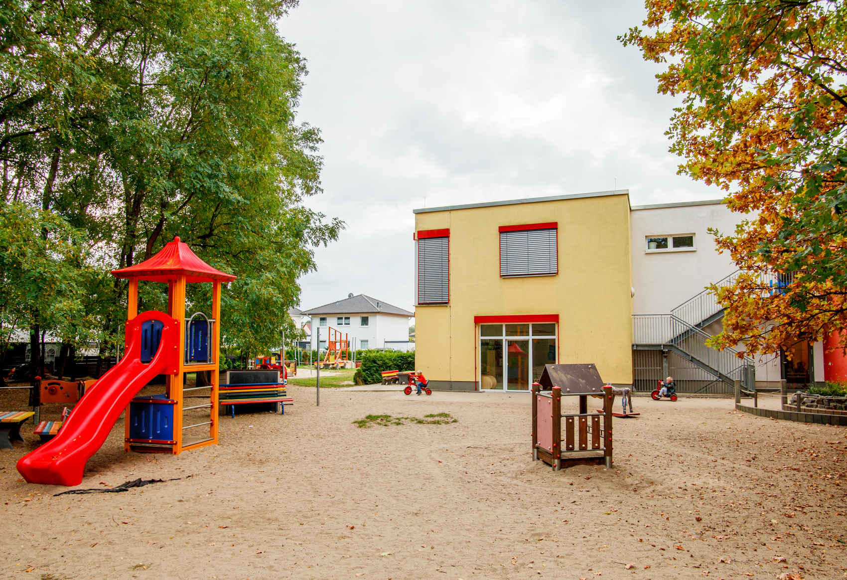Spielplatz mit roter Rutsche und Gebäude im Hintergrund